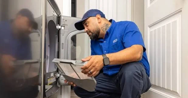 Technician examining a dryer while holding its lint filter